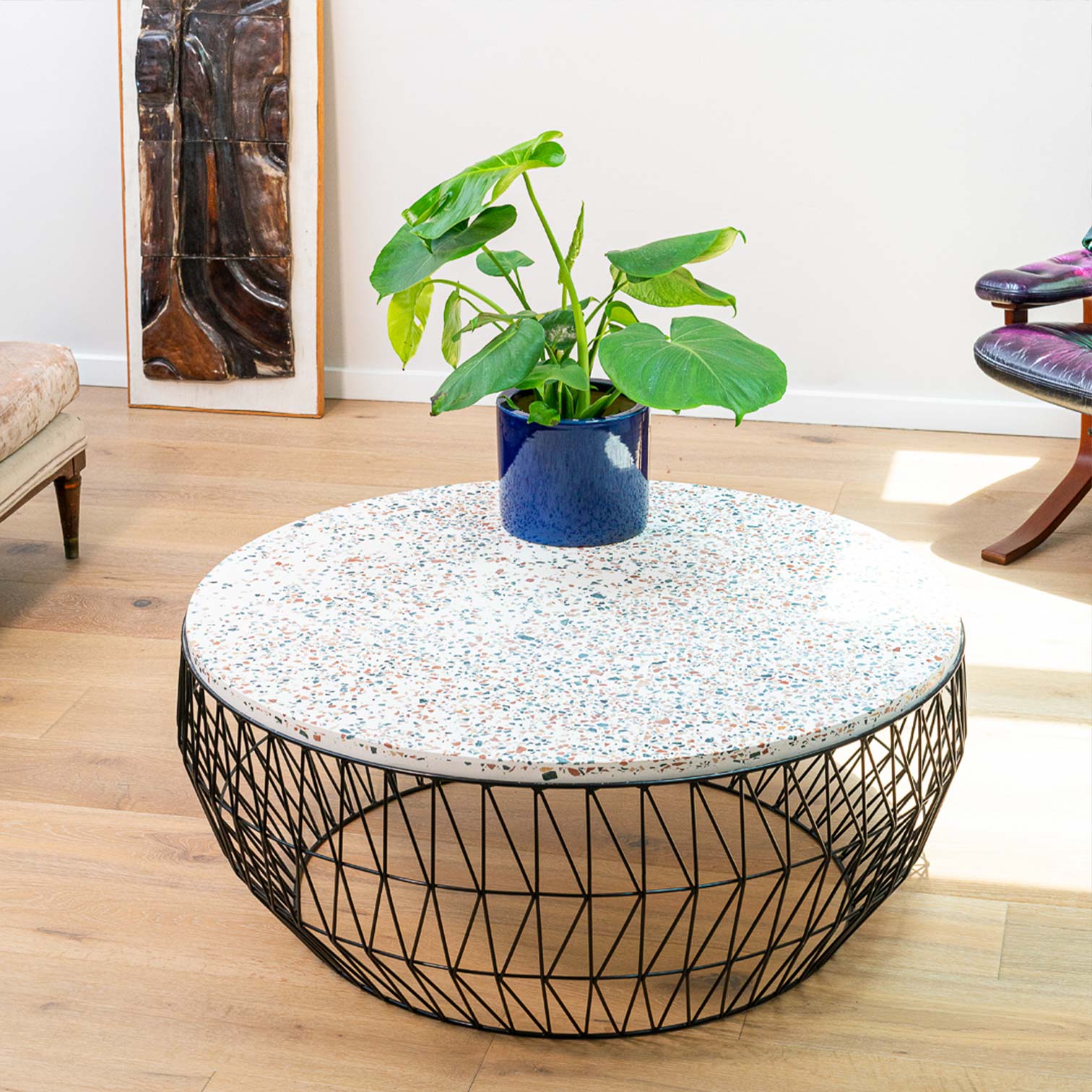 Coffee Table shown in Black with Terrazzo Stone Top. Pictured in bright interior space with wood floors.