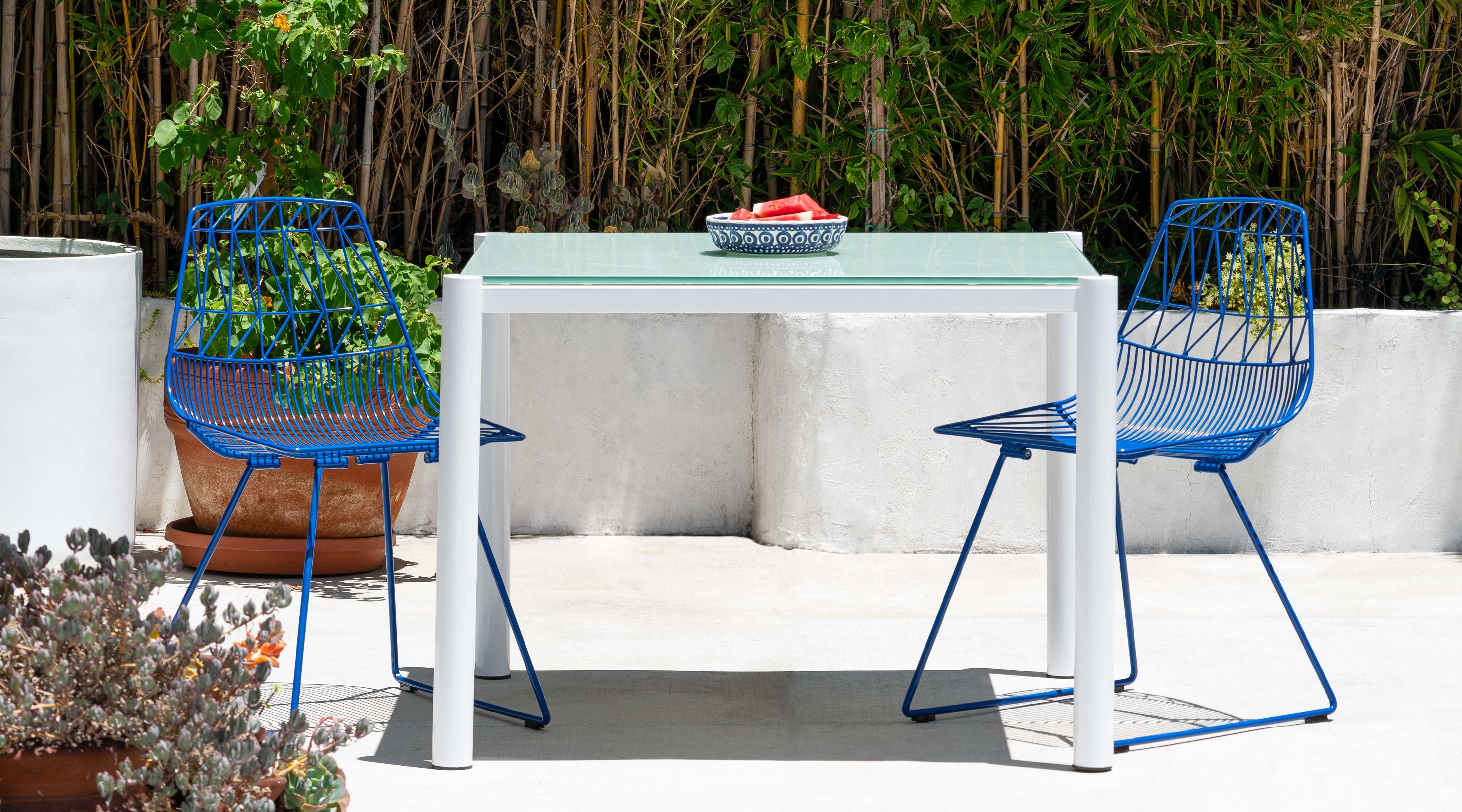 38" Get-Together Table shown in White with Tempered Glass. Pictured with Lucy Side Chairs outdoors.