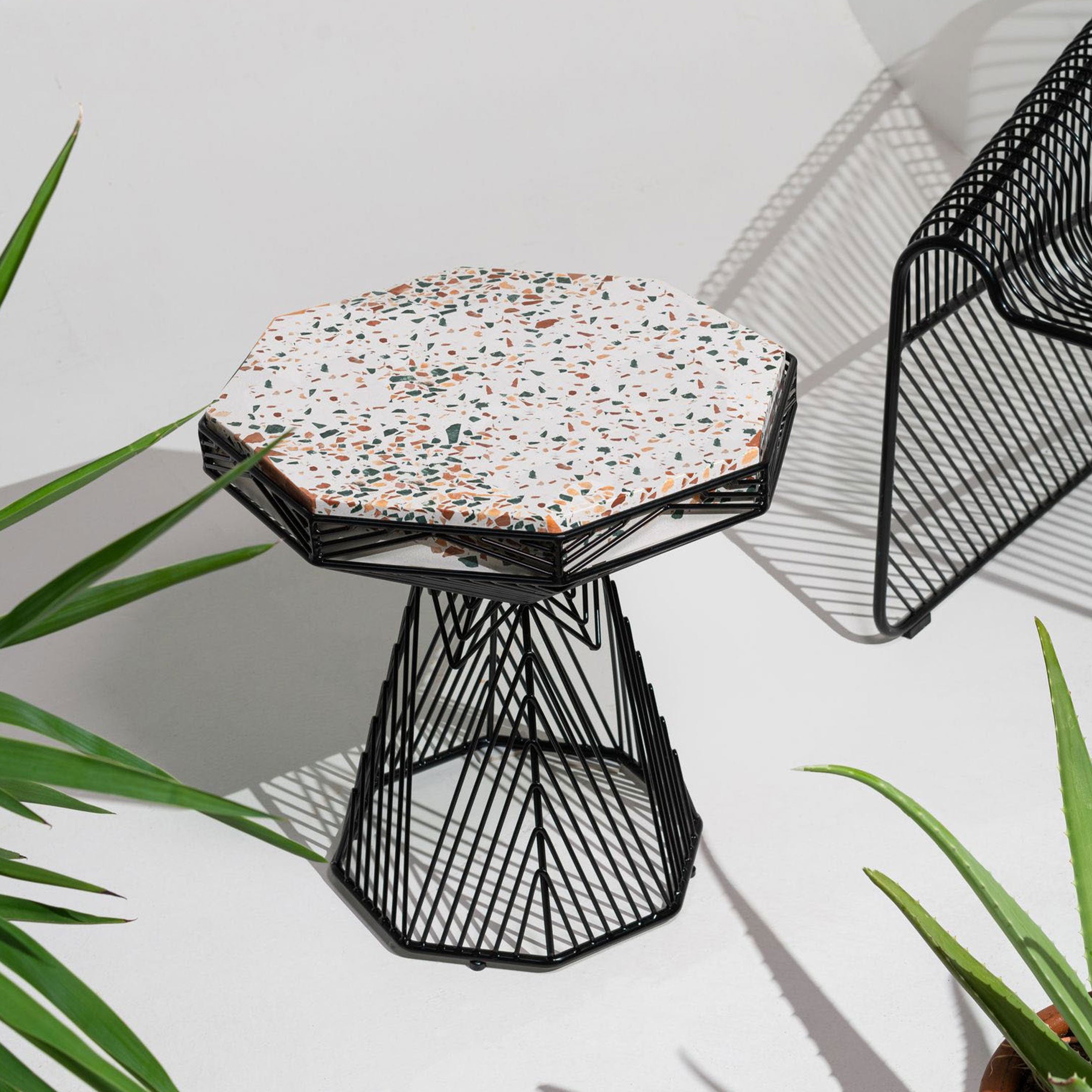 Terrazzo Switch Table shown in Black. Pictured in white room next to the Hot Seat Lounge in Black.