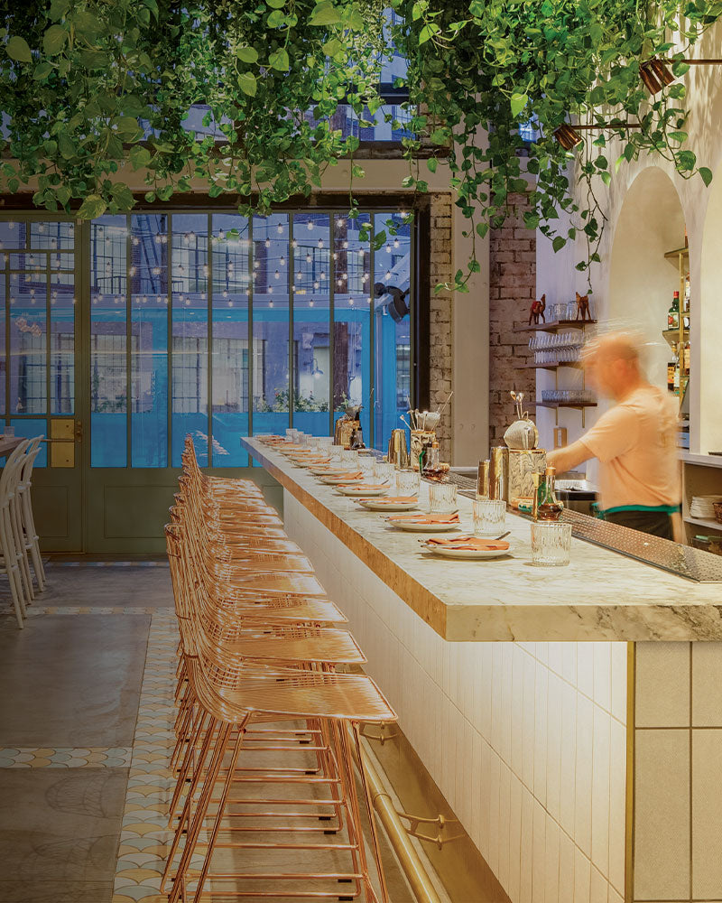 Copper wire bar stools from the Bend Goods collection in a modern restaurant interior