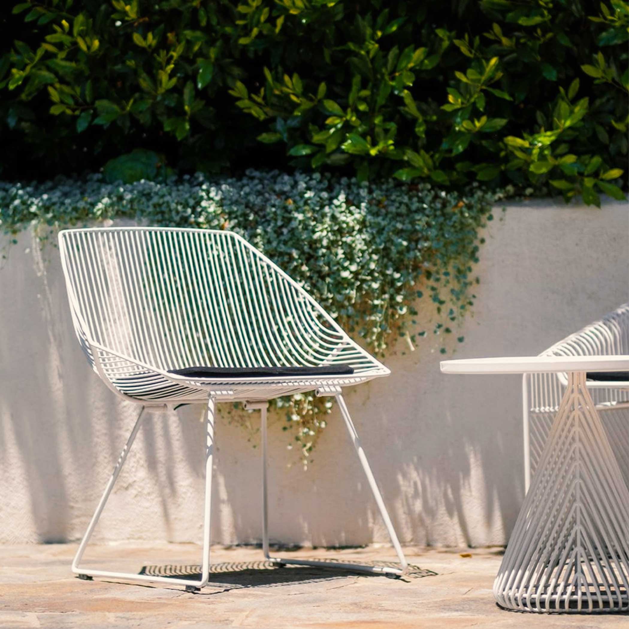 Bunny Lounge Chair shown in White with Black Sunbrella Seat Pad. Pictured alongside the Cono Table & Love Seat Lounge