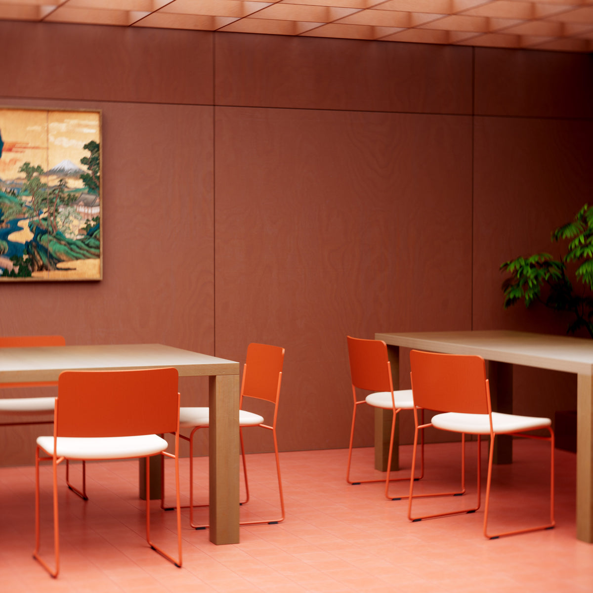 Red Hinoki dining chairs with white seat cushions around wood tables in a red room with landscape art.