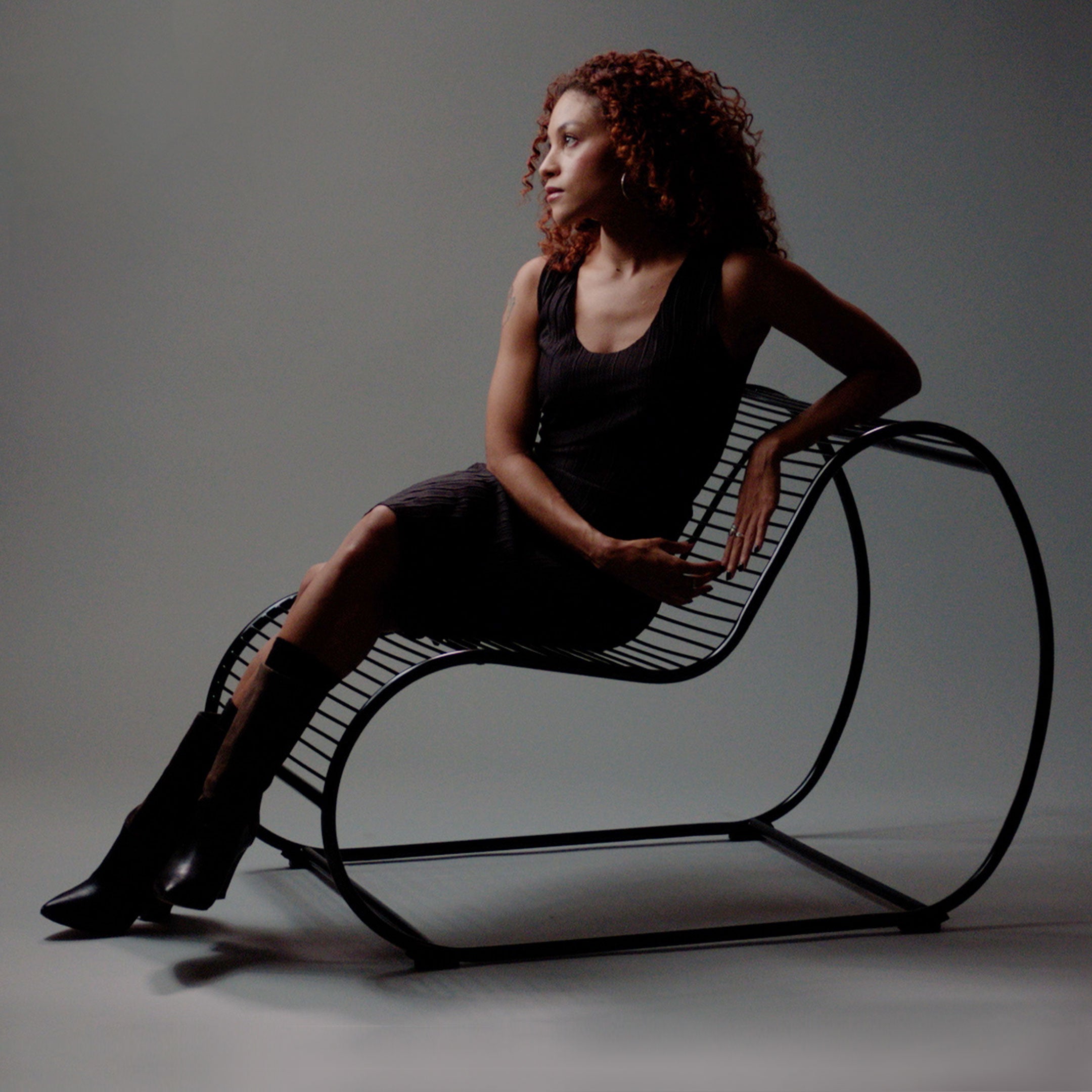 Loop Lounge Chair shown with Woman seating. Image is grey with dynamic shadows