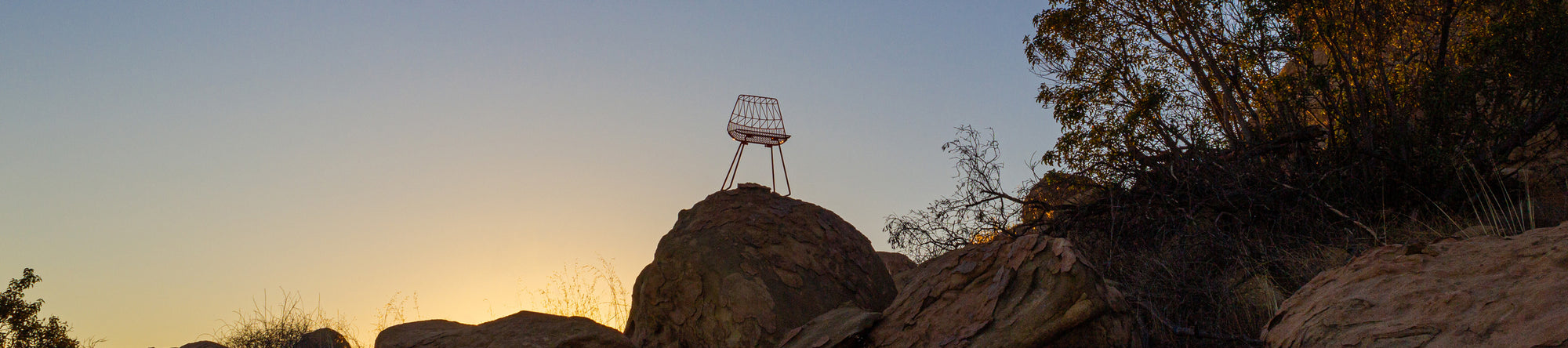 Silhouette of a Lucy Chair on a rock with a sunset or sunrise in the background
